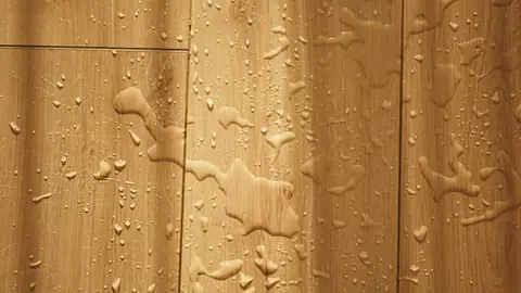 Water droplets beading on wood floorboards
